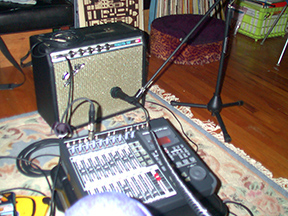 A guitar amp with a microphone set up in front of it in someone\'s living room.